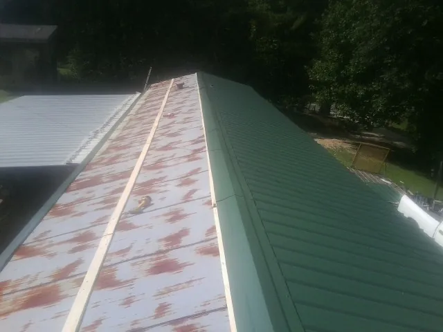Old rusted panels beside newly installed green metal roofing — Wind Damage Roof Repair by Roofing Brothers in Beverly